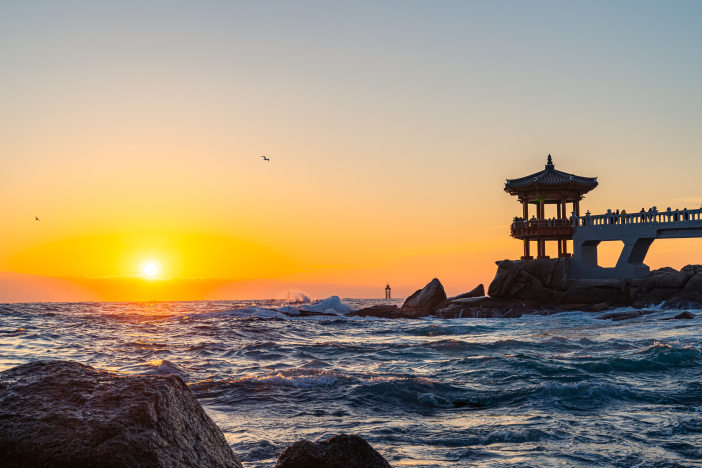 The sun rises from the horizon beyond Yeonggeumjeong Pavilion.