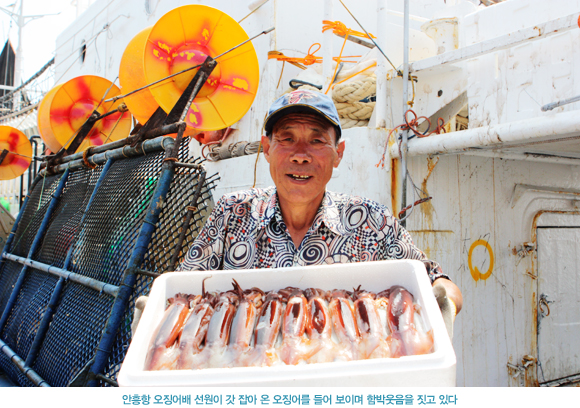 안흥항 오징어배 선원이 갓 잡아 온 오징어를 들어 보이며 함박웃음을 짓고 있다.