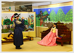 한복을 입고 용상에 앉아 기념촬영하는 남녀