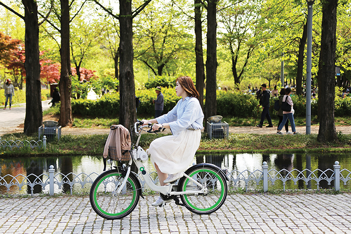 서울숲 내 산책길을 따라 자전거를 타고 가는 여자