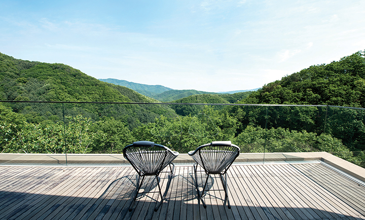 초록의 산만 보이는 야외 테라스에 놓인 의자 두개