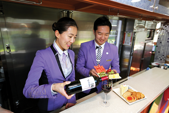 보라색 유니폼을 입은 승무원이 와인과 과일, 과자등을 준비하고 있는 모습