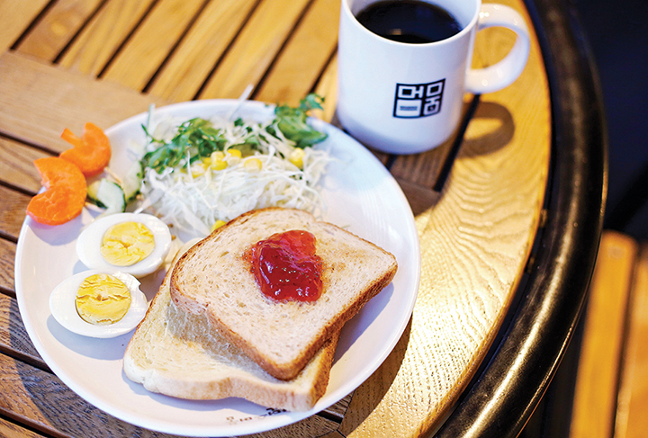 테이블 위 음식(식빵, 삶은 계란, 샐러드)이 담긴 접시와 커피 한잔