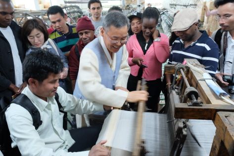 Visitors using the traditional loom to weave fabric 