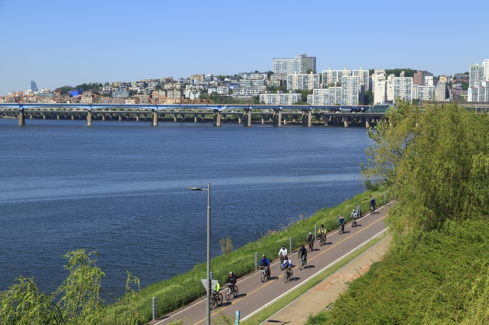 漢江縁に続くサイクリングロードを快走する市民（写真はソウルの森から下流に東湖大橋を眺めた風景）