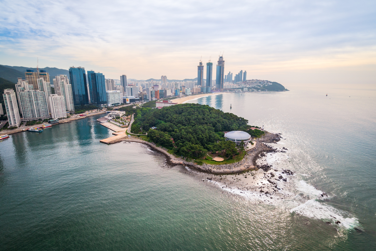 An aerial view of the wooded Dongbaekseom headland and the Marine City high-rises in Haeundae, Busan