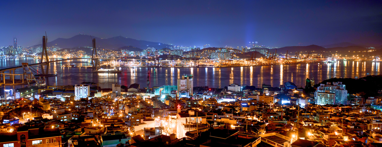 Busan's coastline and city lights at night, with a harbor bridge across the water
