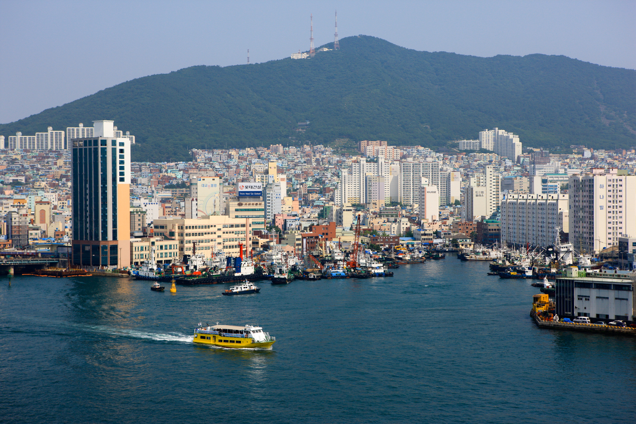 Busan harbor with a ferry, the dense city and a green mountain behind