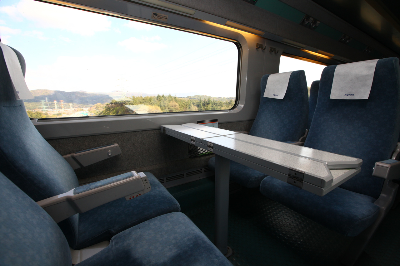 The empty interior of a KTX train with facing seats and a table by the window