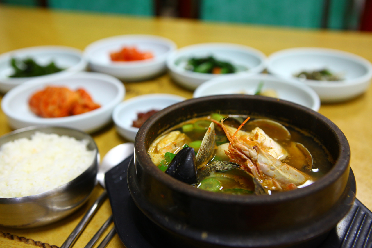 A seafood hot pot with shrimp, clams, and mussels, served with rice and side dishes